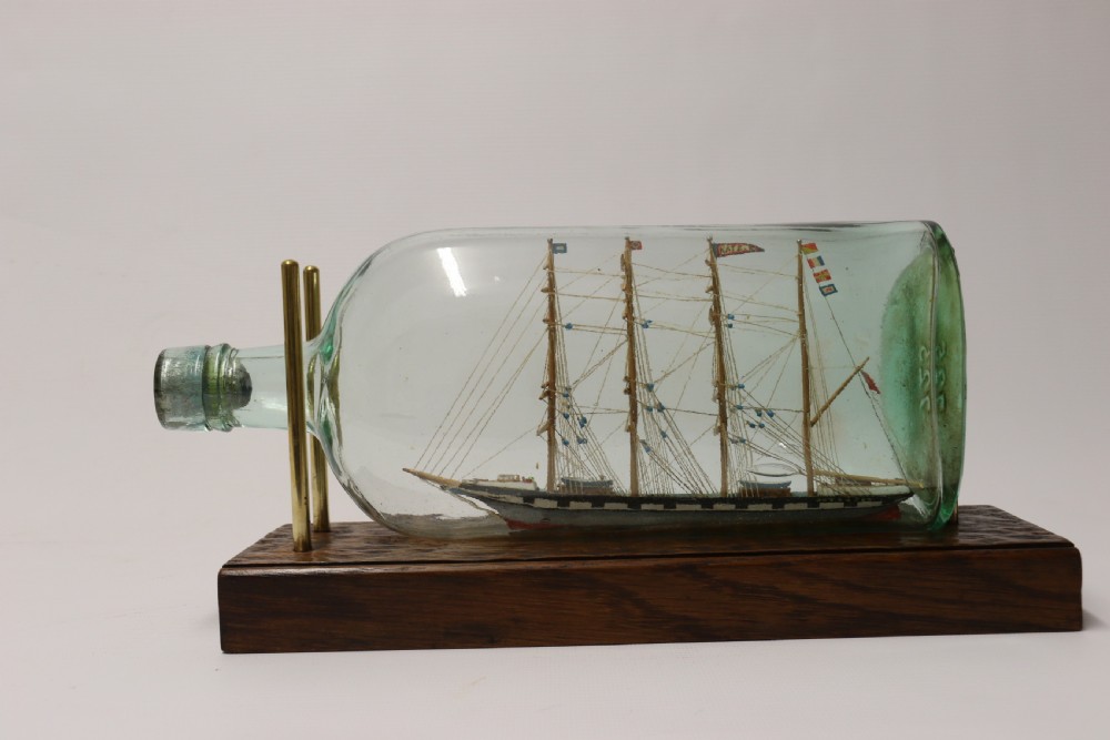 A rare pair of early 20th century model sailing ships in bottles displayed on wooden stands View IX