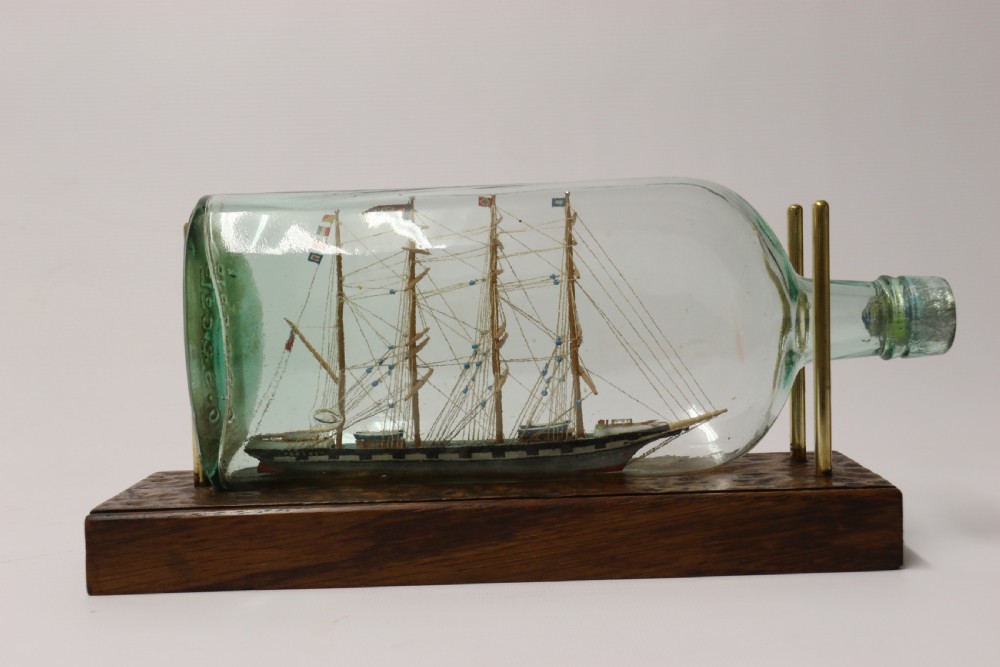 A rare pair of early 20th century model sailing ships in bottles displayed on wooden stands View X