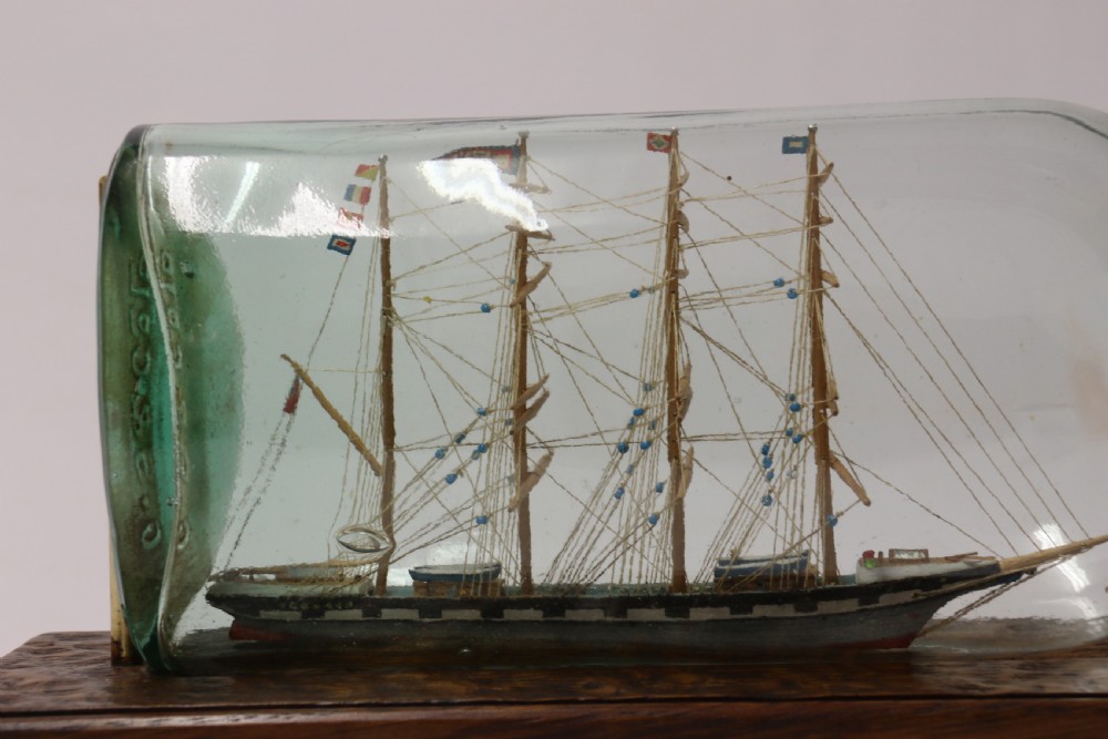 A rare pair of early 20th century model sailing ships in bottles displayed on wooden stands View XI