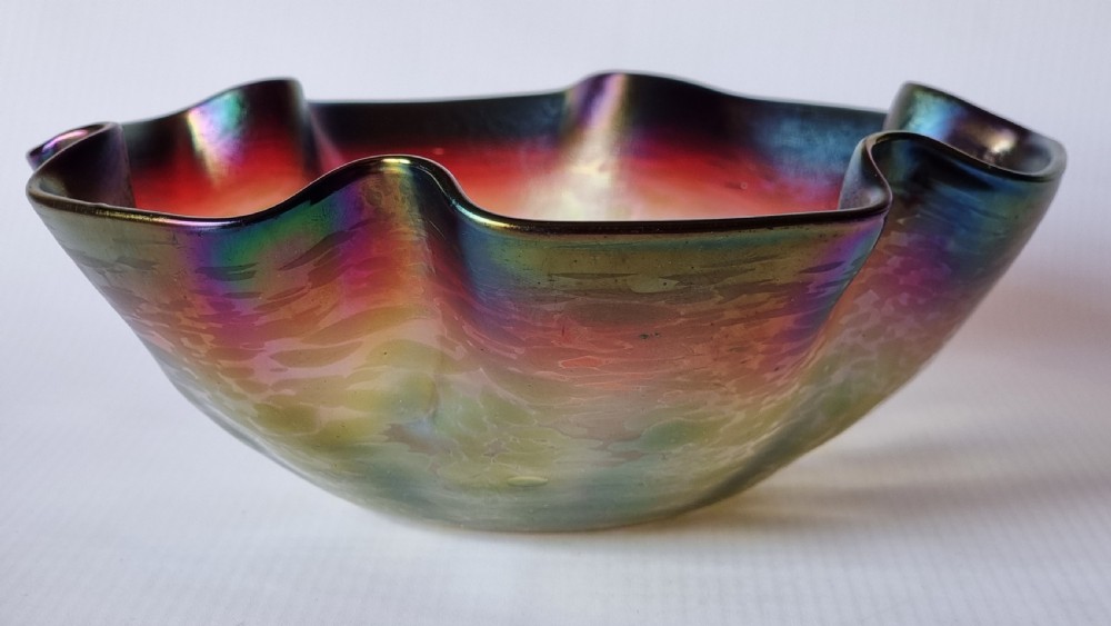 A hand-blown glass bowl featuring an undulating ruffled rim and a shimmering iridescent finish in shades of green, purple, and red. View III
