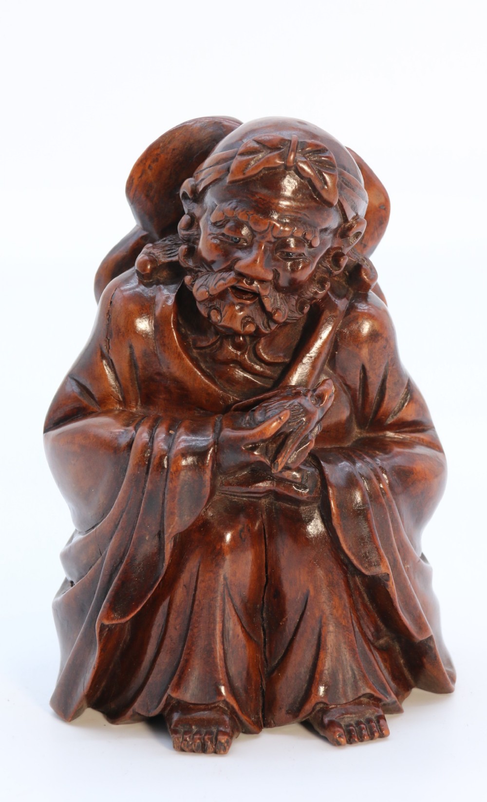A fine Japanese carved hardwood mid 19th century Okimono of a seated man holding a bat.