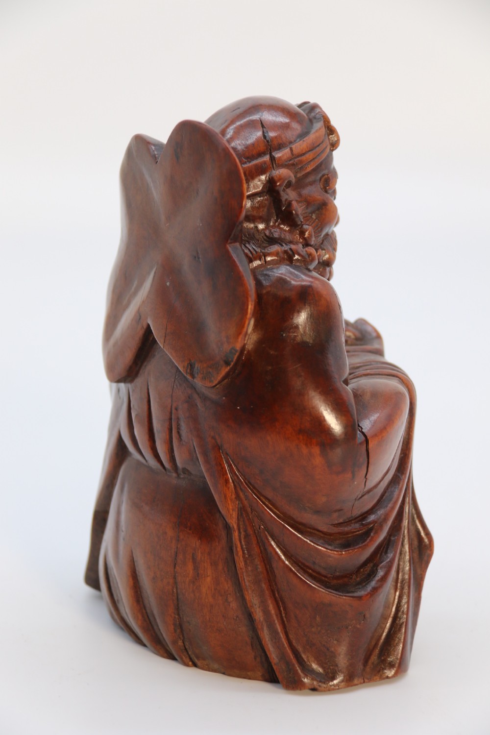 A fine Japanese carved hardwood mid 19th century Okimono of a seated man holding a bat. View V