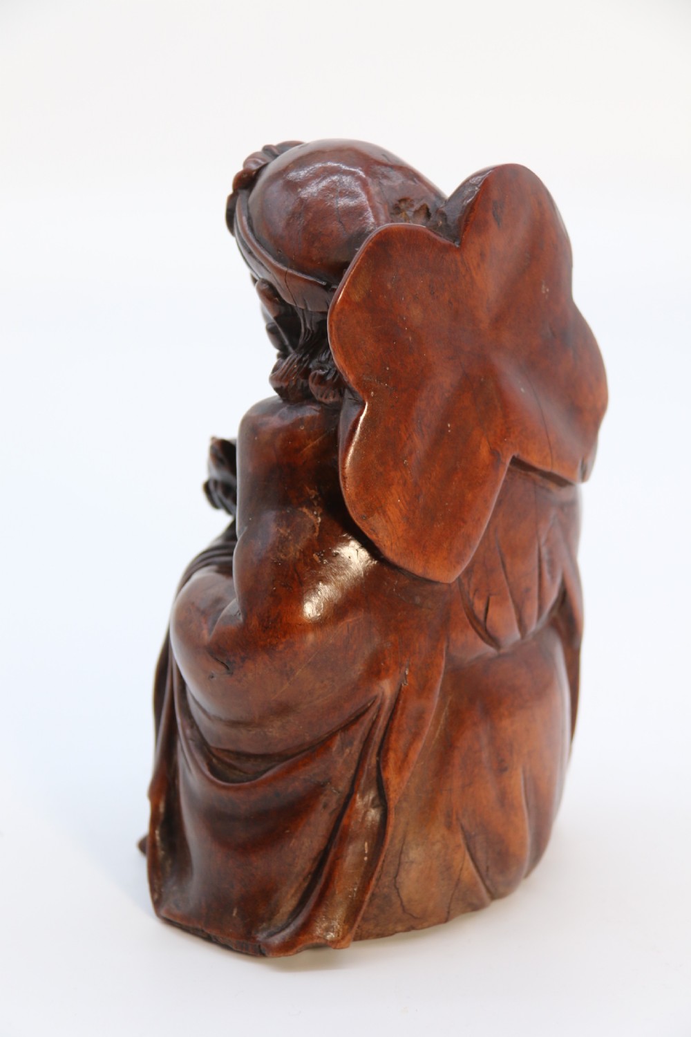 A fine Japanese carved hardwood mid 19th century Okimono of a seated man holding a bat. View VII