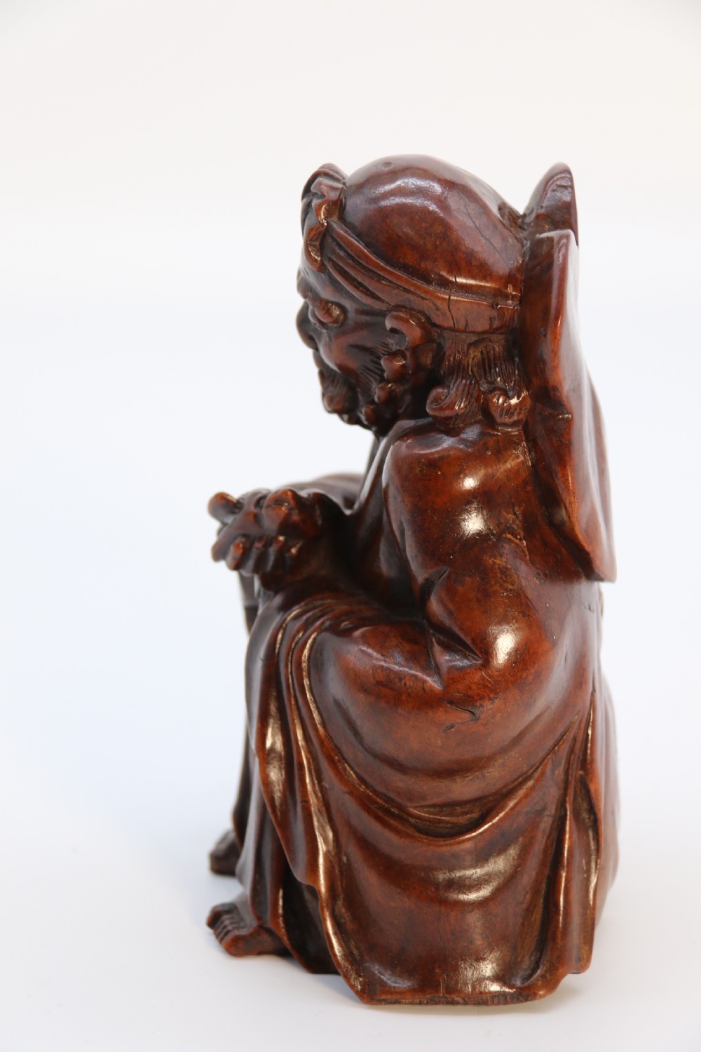 A fine Japanese carved hardwood mid 19th century Okimono of a seated man holding a bat. View VIII