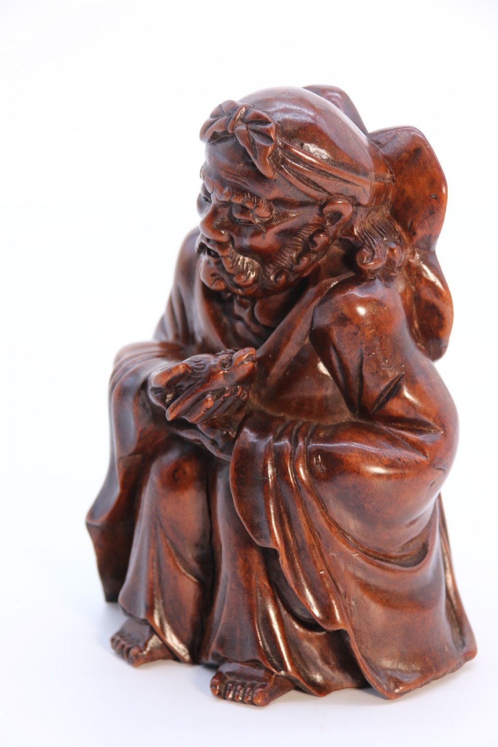 A fine Japanese carved hardwood mid 19th century Okimono of a seated man holding a bat. View IX