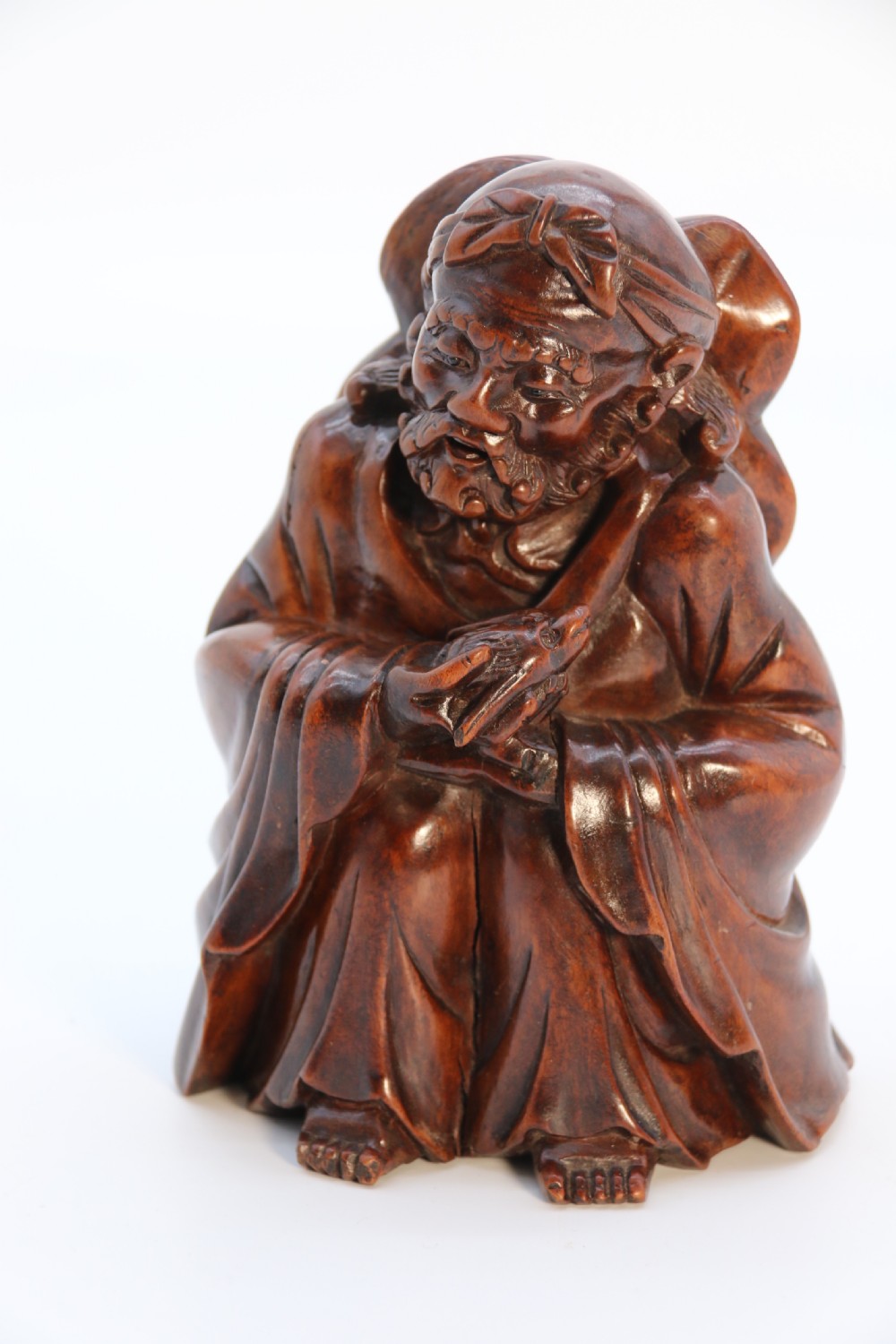 A fine Japanese carved hardwood mid 19th century Okimono of a seated man holding a bat. View X