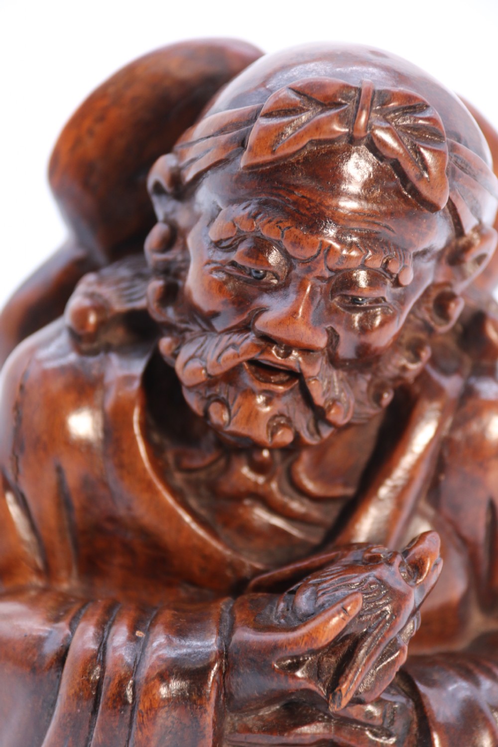 A fine Japanese carved hardwood mid 19th century Okimono of a seated man holding a bat. View XII