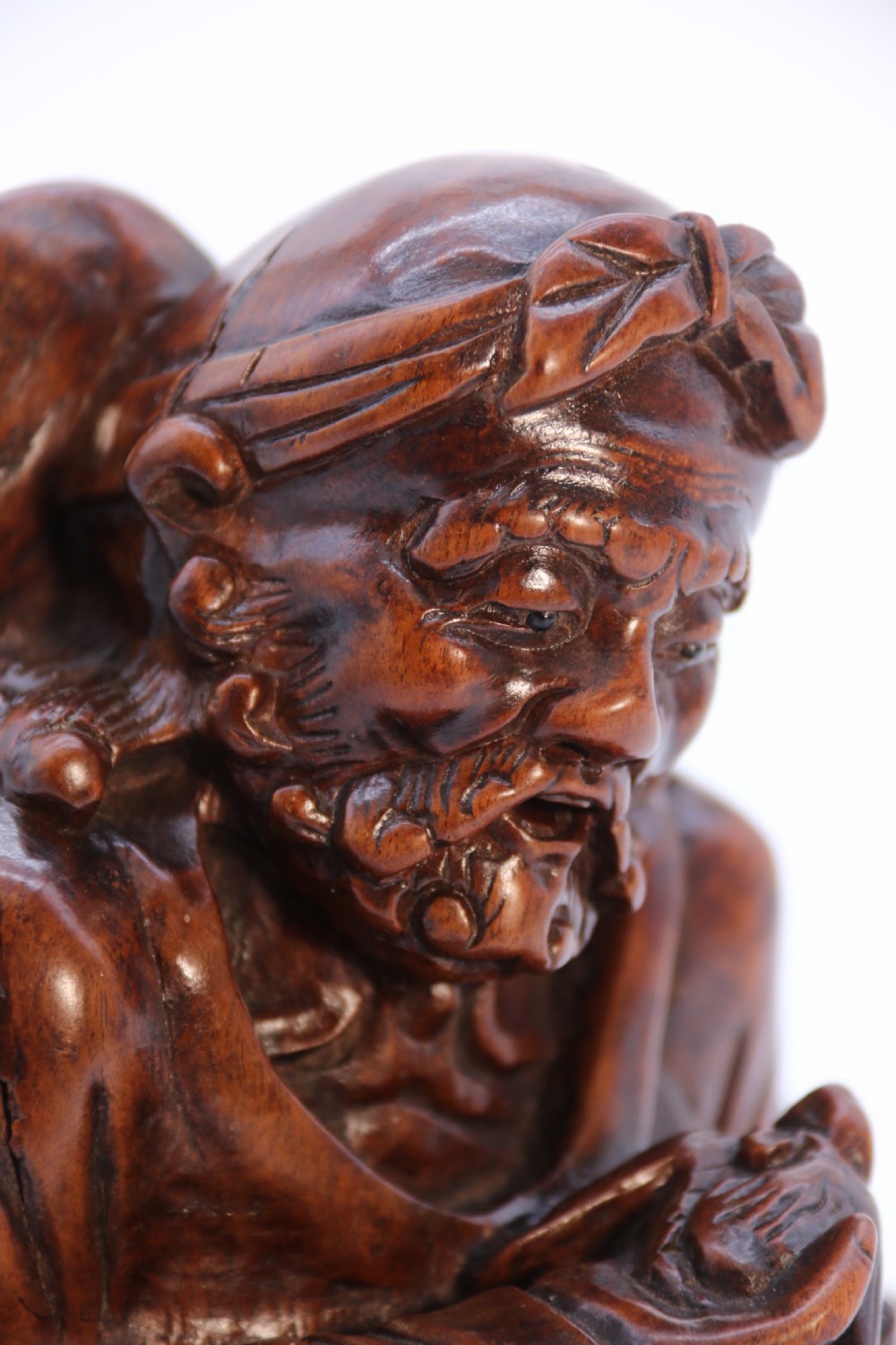 A fine Japanese carved hardwood mid 19th century Okimono of a seated man holding a bat. View XIII