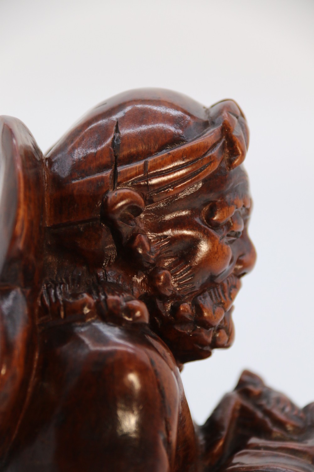 A fine Japanese carved hardwood mid 19th century Okimono of a seated man holding a bat. View XIV