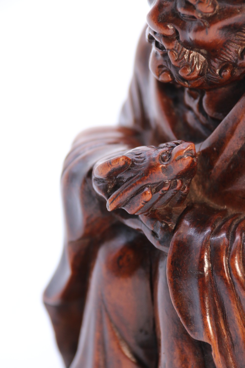 A fine Japanese carved hardwood mid 19th century Okimono of a seated man holding a bat. View XV