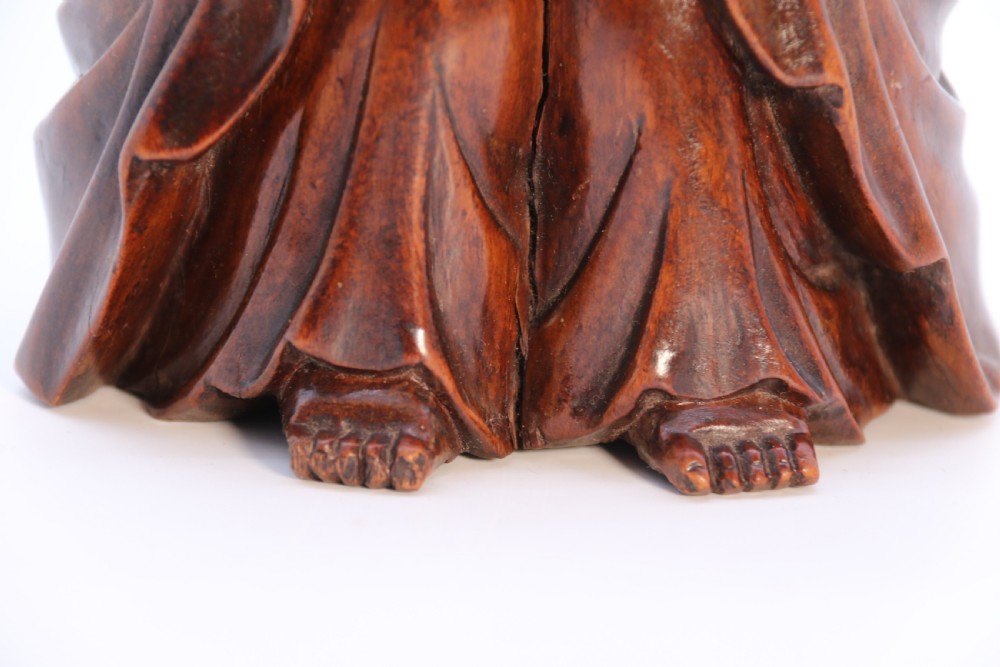 A fine Japanese carved hardwood mid 19th century Okimono of a seated man holding a bat. View XVI