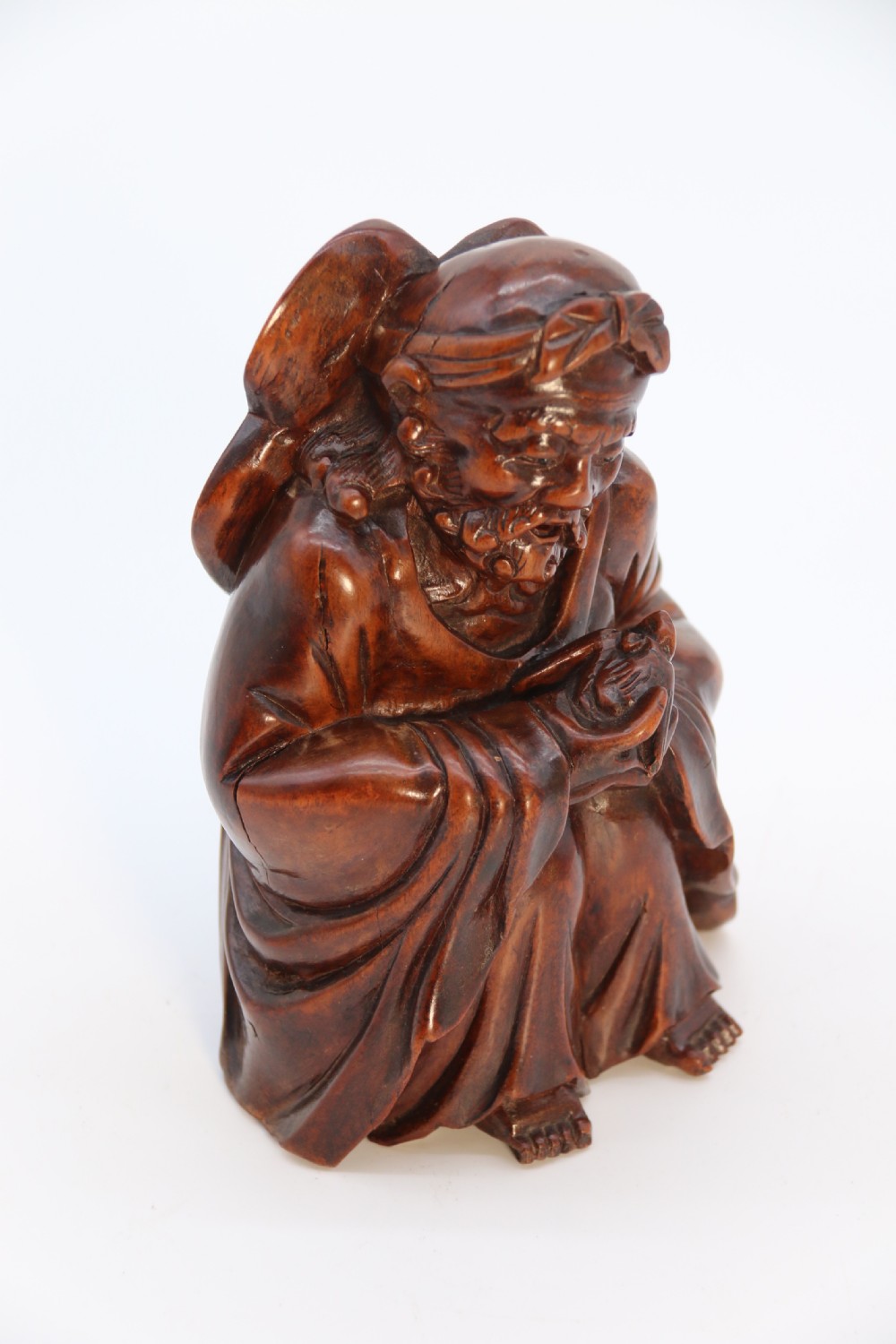 A fine Japanese carved hardwood mid 19th century Okimono of a seated man holding a bat. View XVII