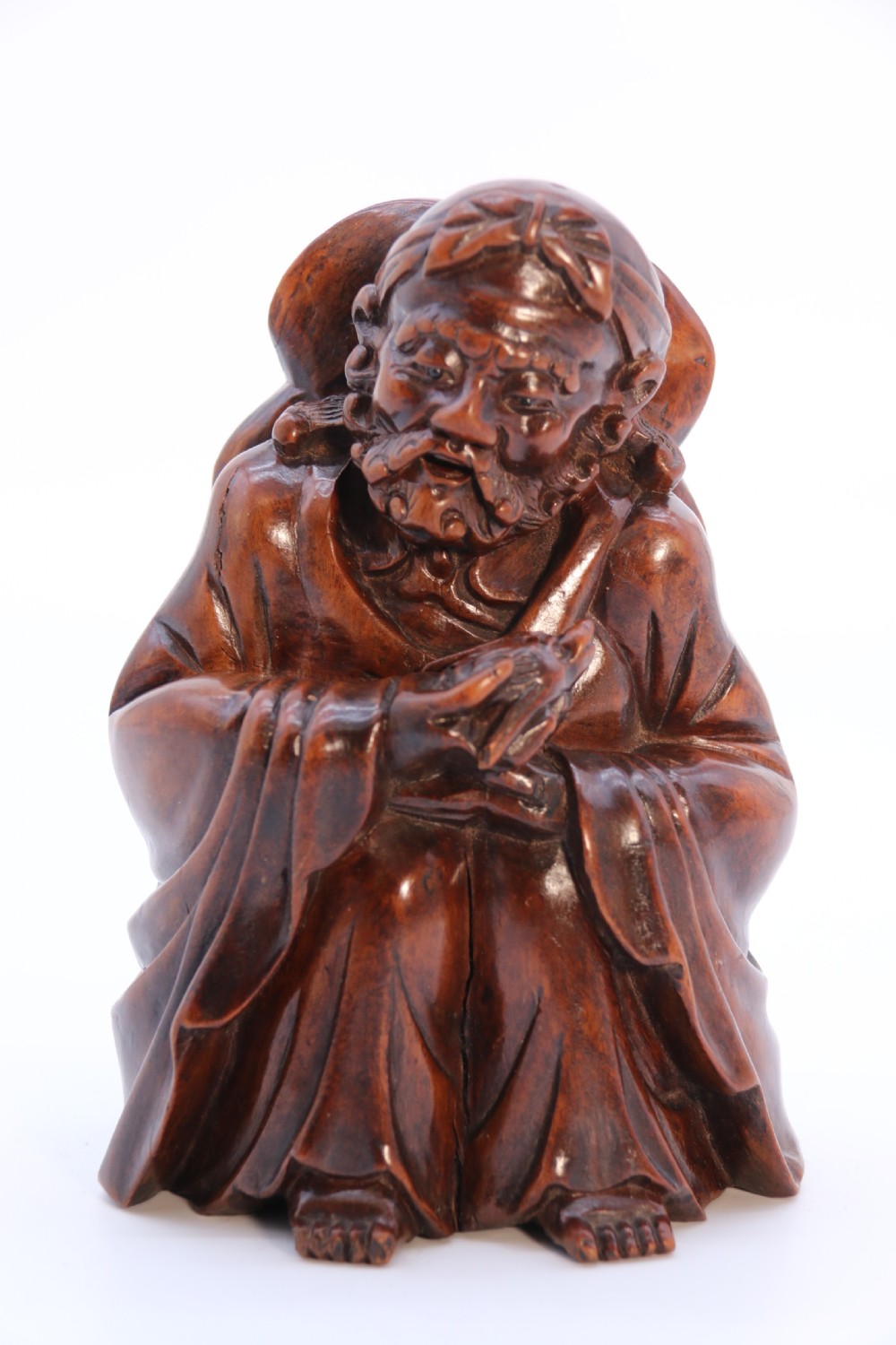 A fine Japanese carved hardwood mid 19th century Okimono of a seated man holding a bat. View XVIII