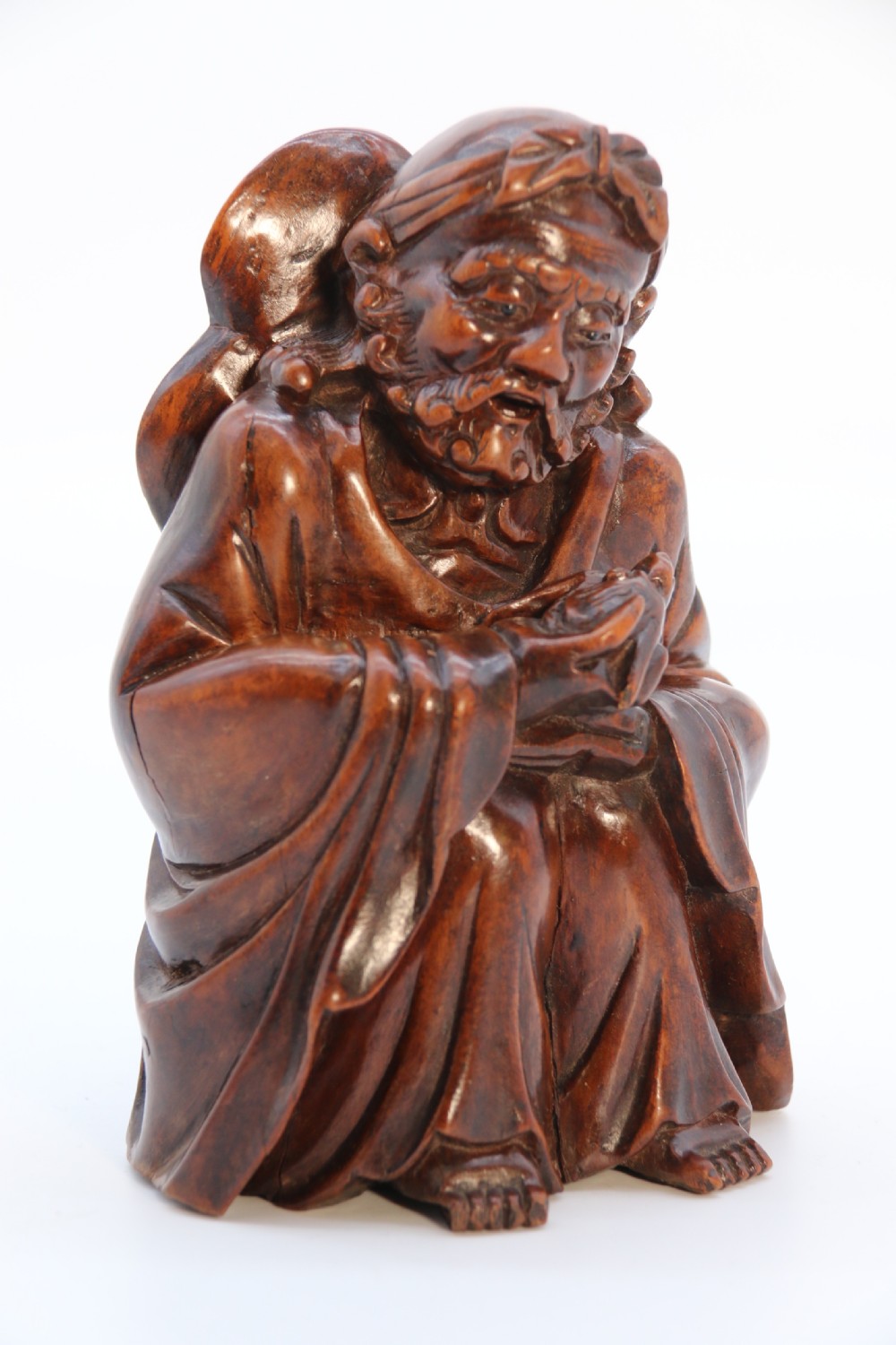 A fine Japanese carved hardwood mid 19th century Okimono of a seated man holding a bat. View XIX