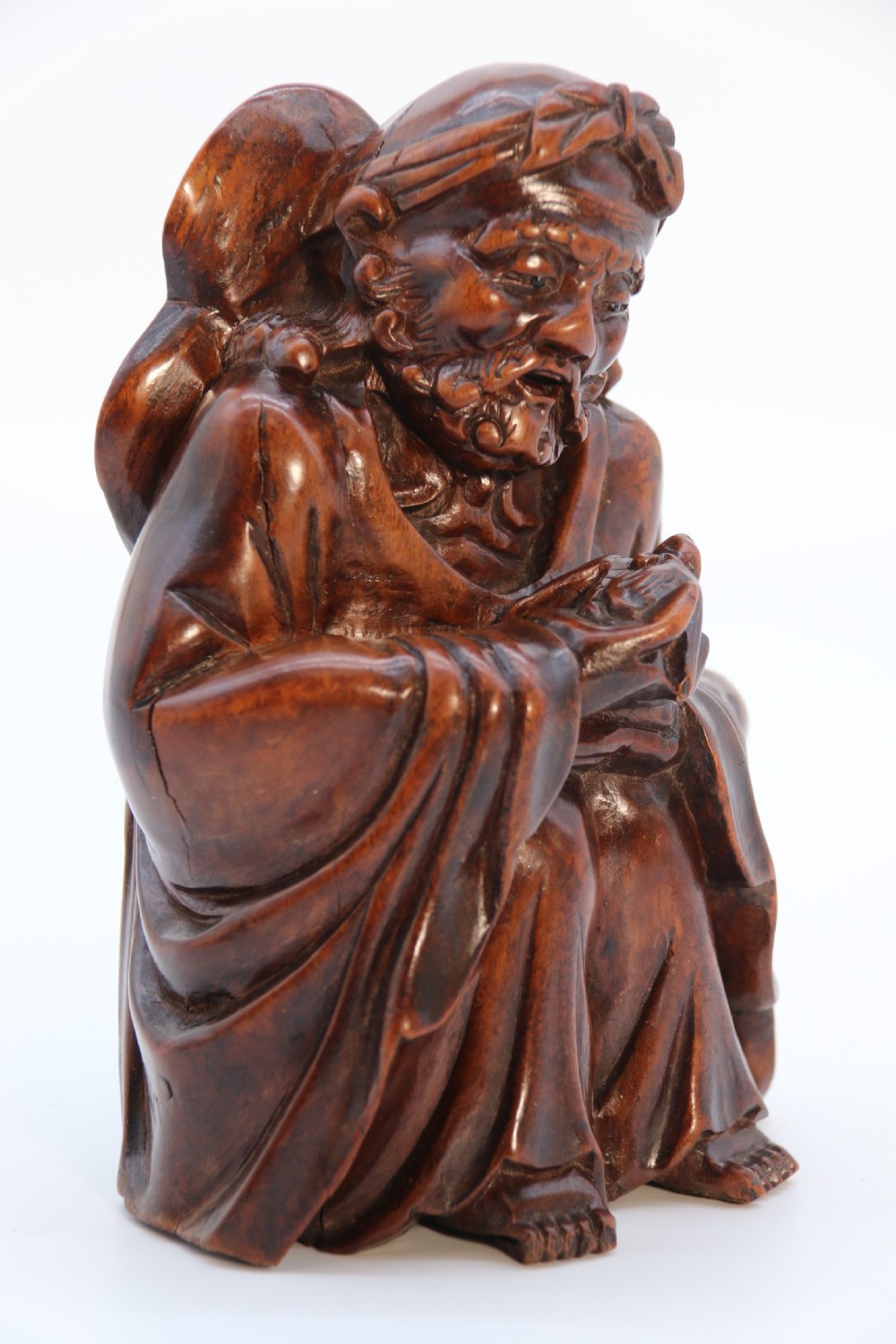 A fine Japanese carved hardwood mid 19th century Okimono of a seated man holding a bat. View XX