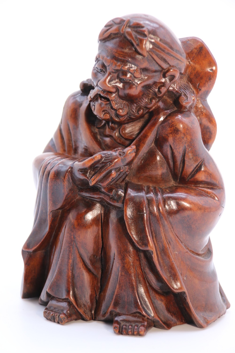 A fine Japanese carved hardwood mid 19th century Okimono of a seated man holding a bat. View XXI