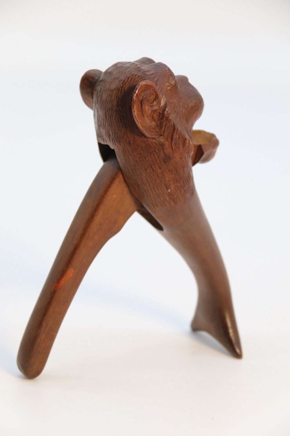A hand-carved walnut nutcracker shaped as a monkey head with glass bead eyes and a hinged jaw mechanism. View III
