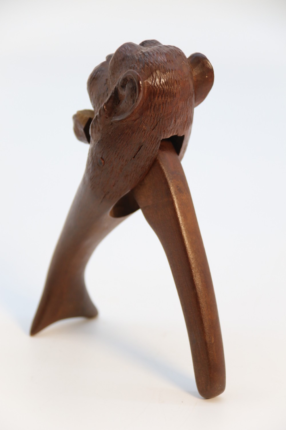 A hand-carved walnut nutcracker shaped as a monkey head with glass bead eyes and a hinged jaw mechanism. View V