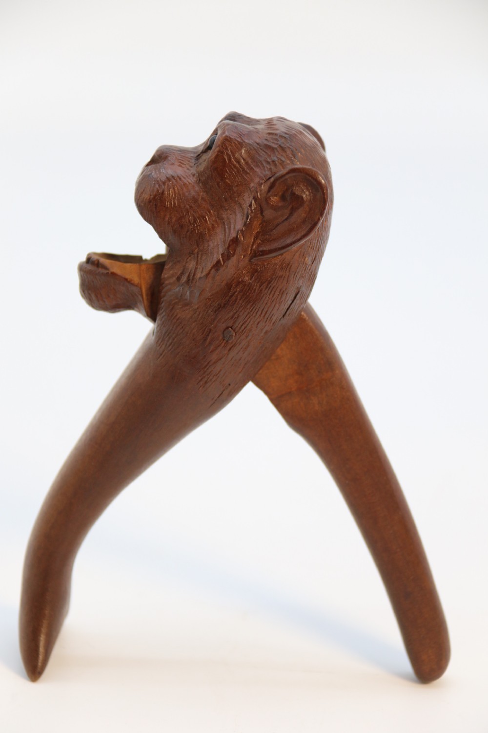 A hand-carved walnut nutcracker shaped as a monkey head with glass bead eyes and a hinged jaw mechanism. View VI