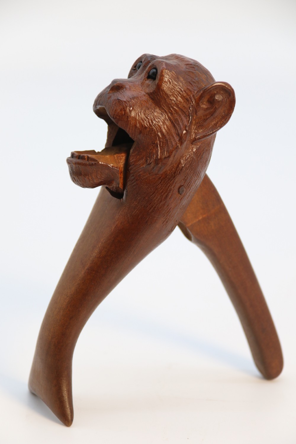 A hand-carved walnut nutcracker shaped as a monkey head with glass bead eyes and a hinged jaw mechanism. View VII