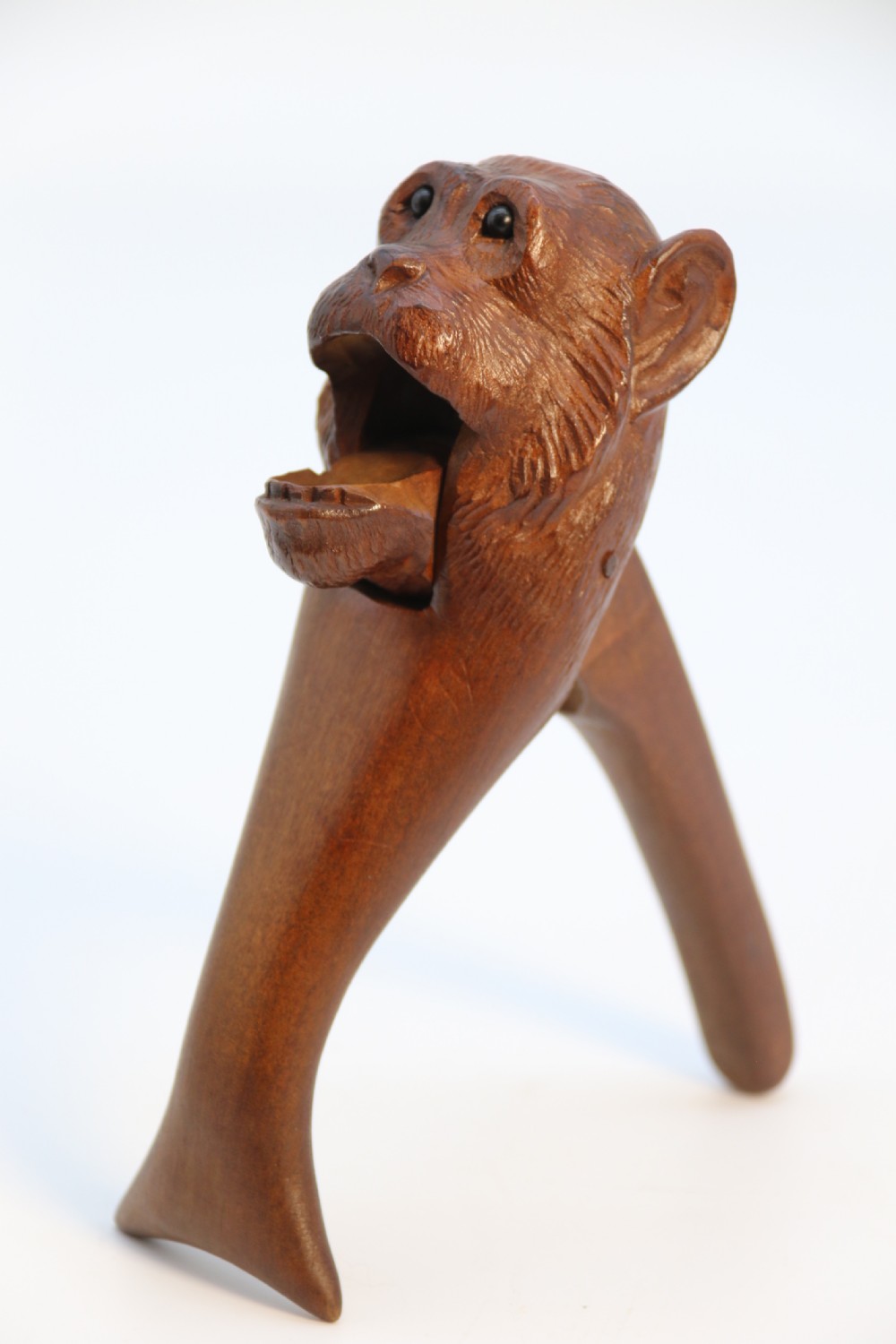 A hand-carved walnut nutcracker shaped as a monkey head with glass bead eyes and a hinged jaw mechanism. View VIII