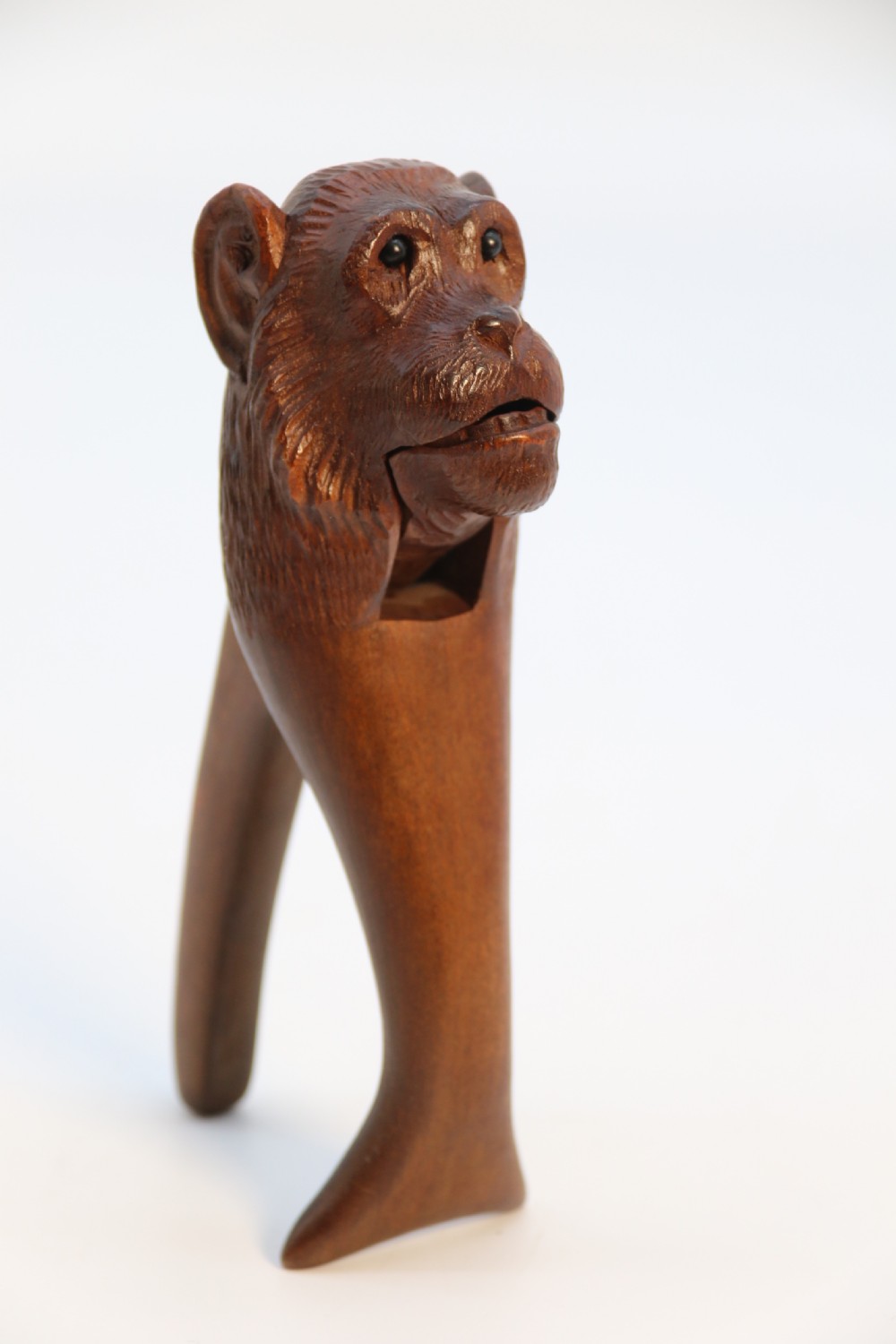 A hand-carved walnut nutcracker shaped as a monkey head with glass bead eyes and a hinged jaw mechanism. View IX