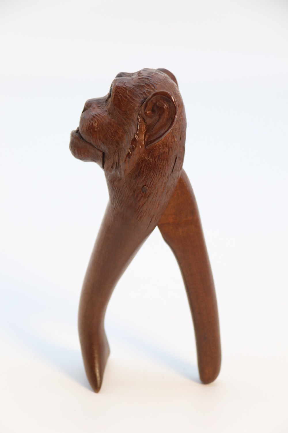 A hand-carved walnut nutcracker shaped as a monkey head with glass bead eyes and a hinged jaw mechanism. View XII