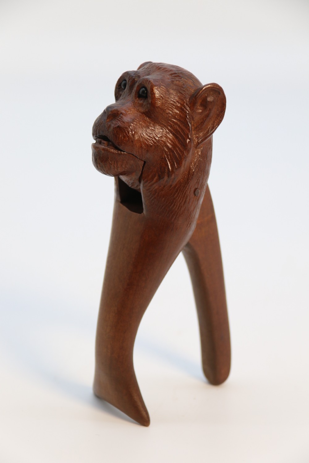 A hand-carved walnut nutcracker shaped as a monkey head with glass bead eyes and a hinged jaw mechanism. View XIII
