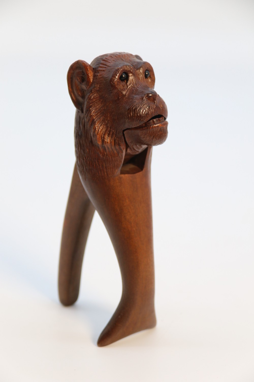 A hand-carved walnut nutcracker shaped as a monkey head with glass bead eyes and a hinged jaw mechanism. View XIV
