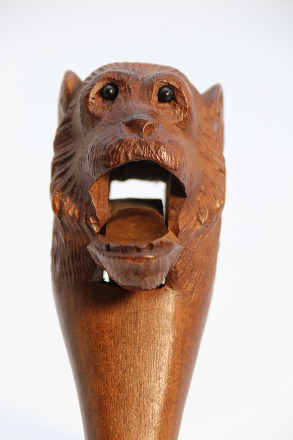 A hand-carved walnut nutcracker shaped as a monkey head with glass bead eyes and a hinged jaw mechanism. View XVI