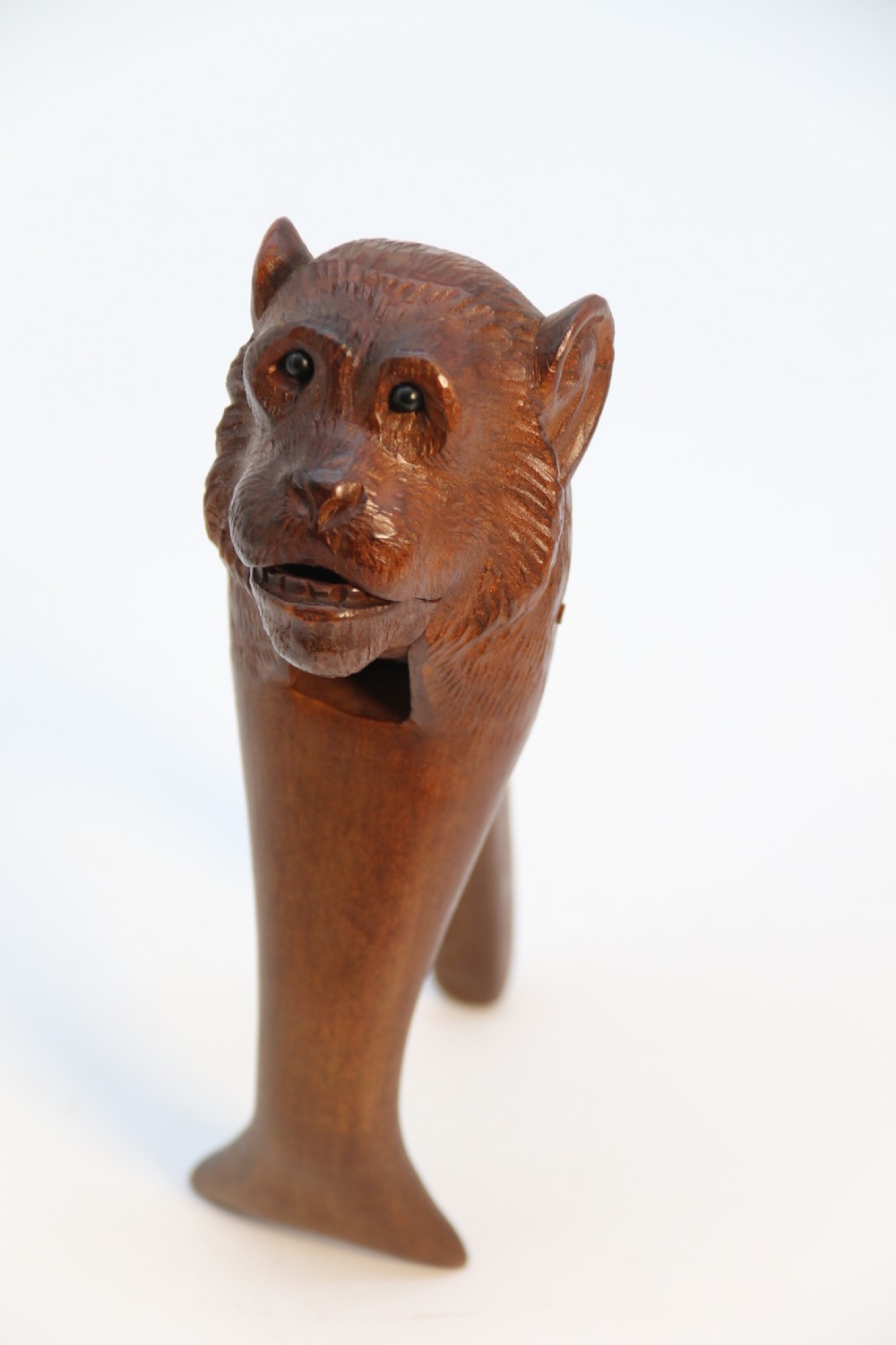 A hand-carved walnut nutcracker shaped as a monkey head with glass bead eyes and a hinged jaw mechanism. View XX