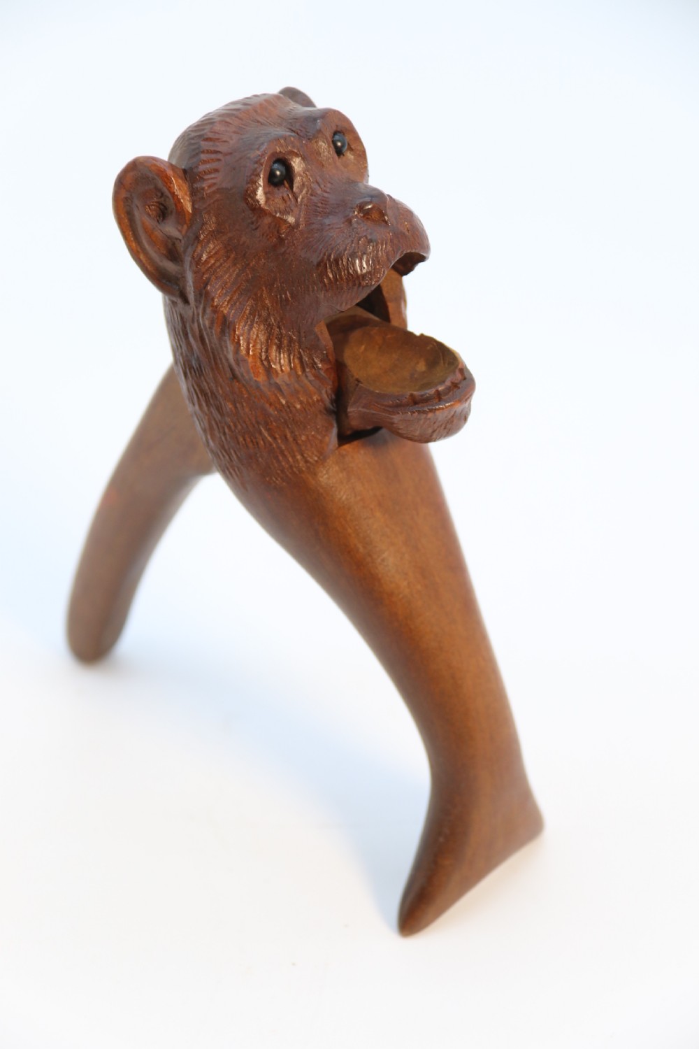 A hand-carved walnut nutcracker shaped as a monkey head with glass bead eyes and a hinged jaw mechanism. View XXI