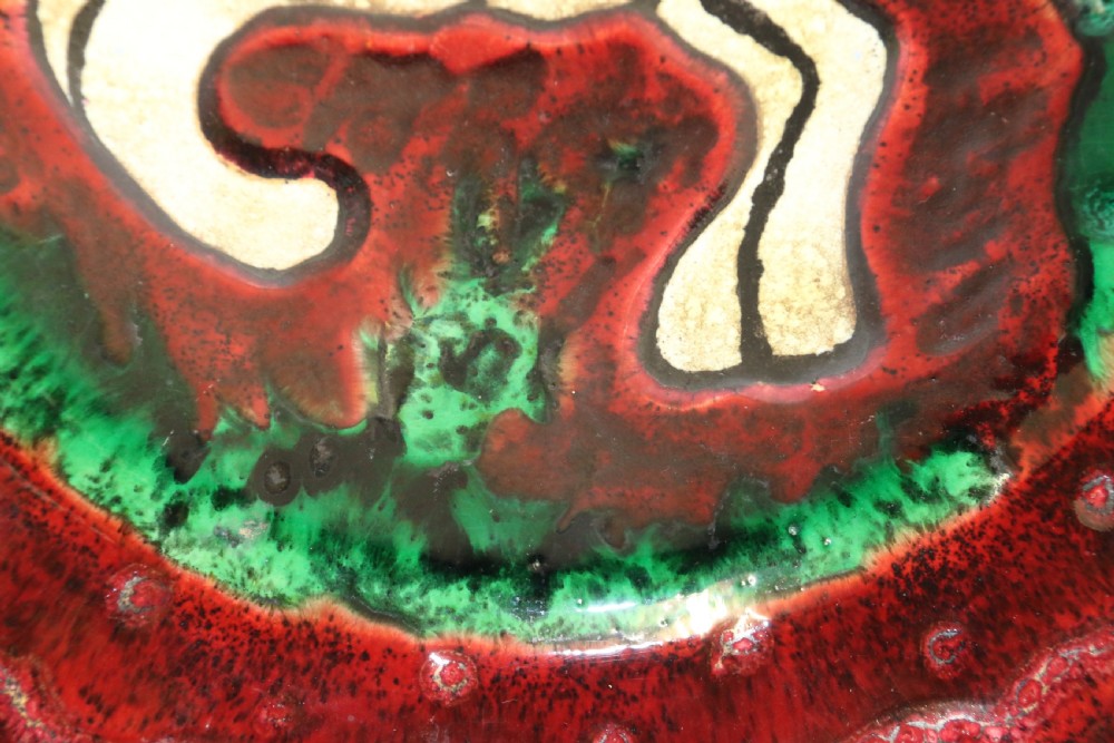 A circular glazed ceramic charger featuring a stylised cream horse motif against a deep red and emerald green reactive glaze. View III