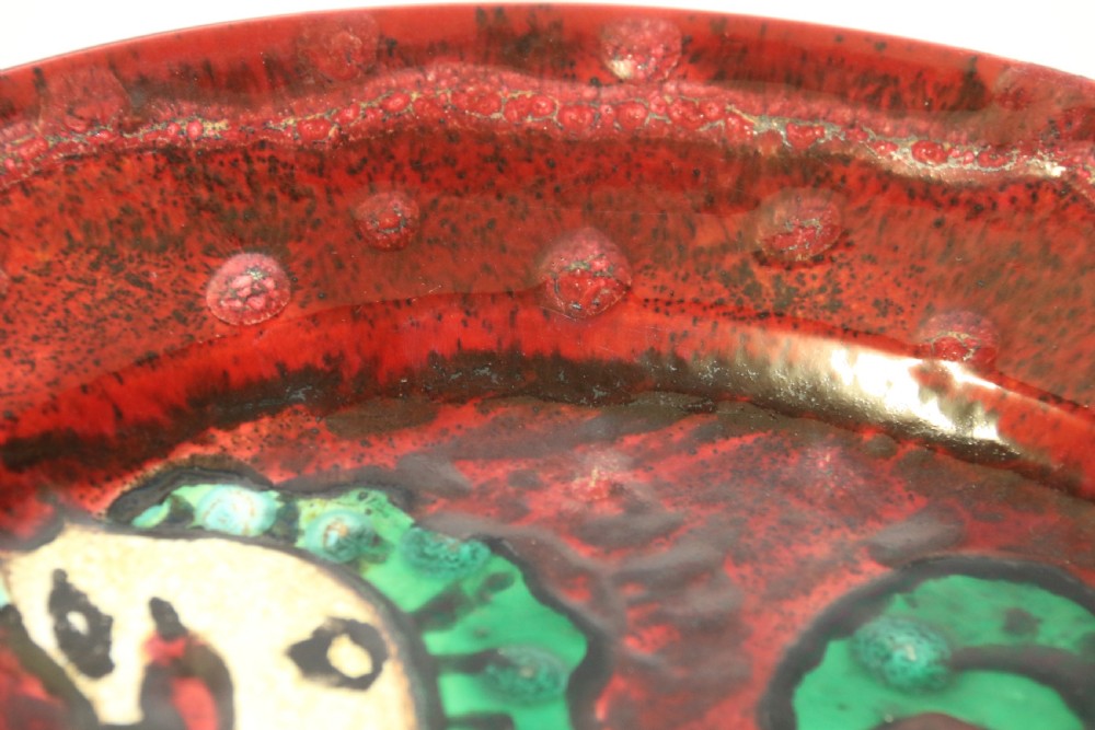 A circular glazed ceramic charger featuring a stylised cream horse motif against a deep red and emerald green reactive glaze. View XI