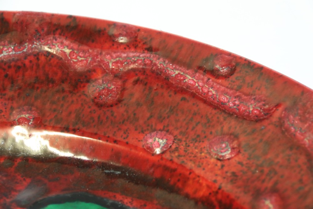 A circular glazed ceramic charger featuring a stylised cream horse motif against a deep red and emerald green reactive glaze. View XIV