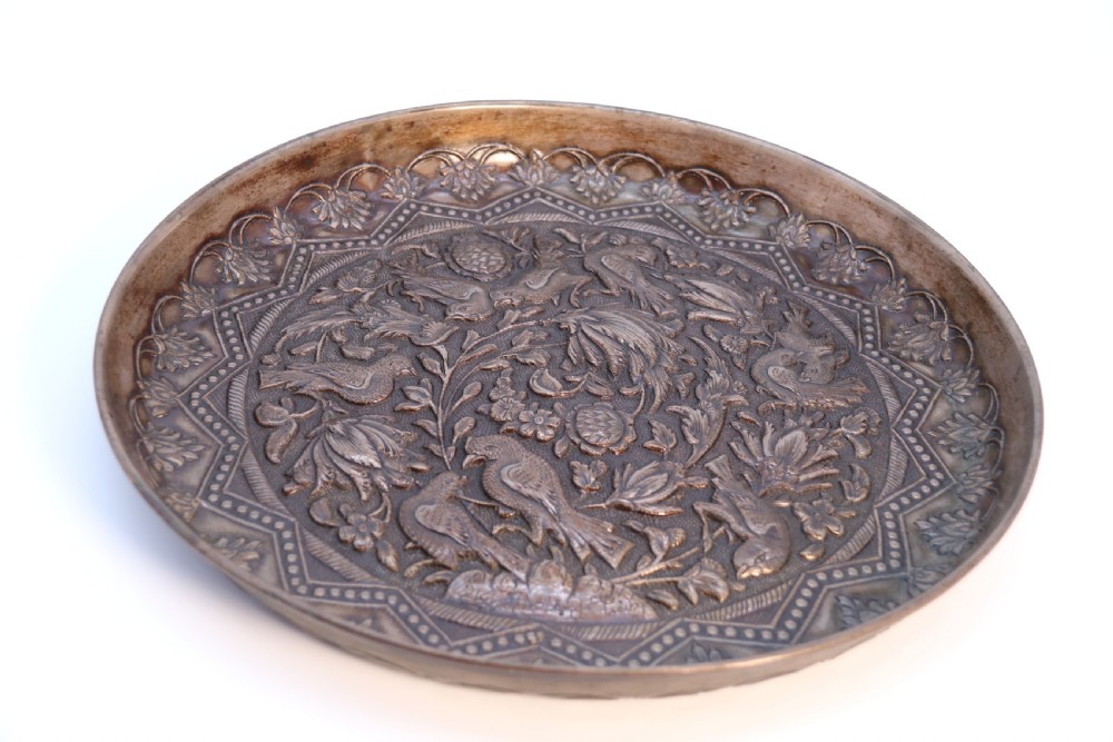A circular copper repousse charger featuring relief carvings of birds, flowers, and geometric borders. View XIII