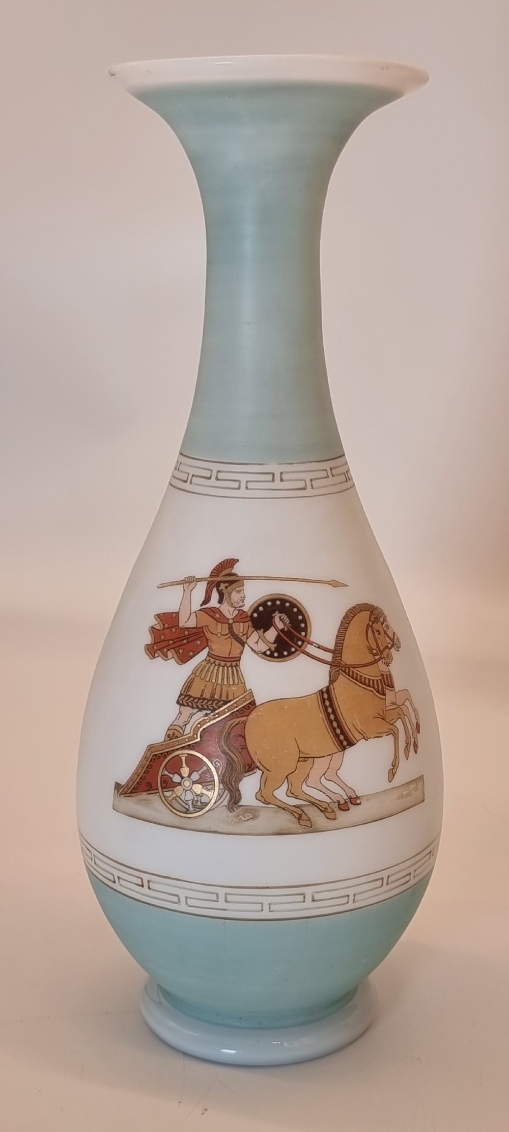 A late nineteenth-century opaque white and light blue glass vase decorated with a hand-painted scene of a Greek chariot and warrior bordered by Greek key patterns.