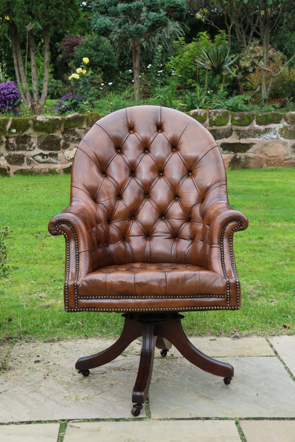 An English tilt and rotate desk/study armchair upholstered in original deep buttoned leather. View II