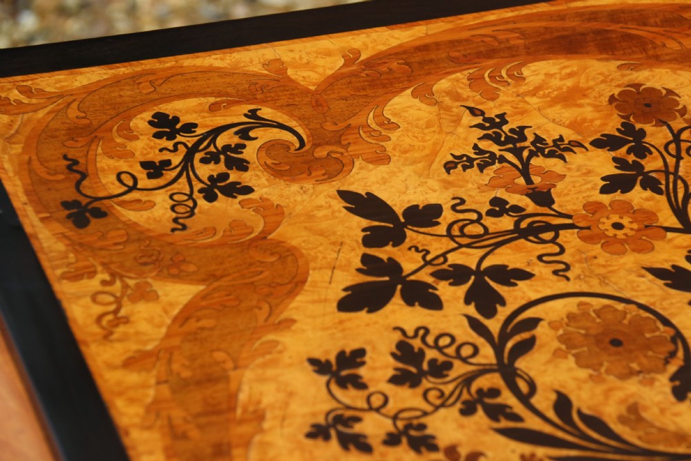 A rectangular mid-19th century satinwood centre table featuring detailed floral marquetry inlay across the tabletop, supported by carved barley twist legs and a central stretcher. View II