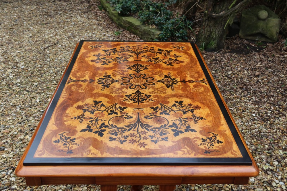 A rectangular mid-19th century satinwood centre table featuring detailed floral marquetry inlay across the tabletop, supported by carved barley twist legs and a central stretcher. View XIX