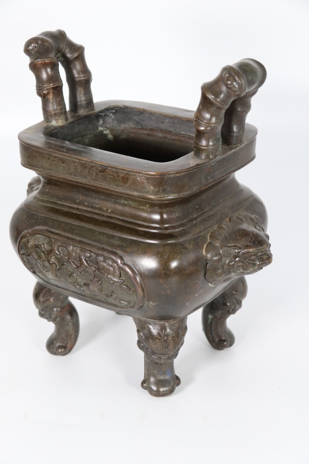 A 19th-century Chinese cast bronze incense censer featuring a lid surmounted by a guardian lion finial, relief panels, and animal-mask handles, set upon a matching bronze base. View XIII