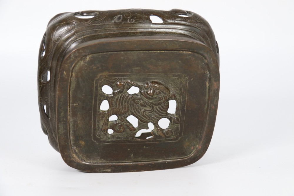 A 19th-century Chinese cast bronze incense censer featuring a lid surmounted by a guardian lion finial, relief panels, and animal-mask handles, set upon a matching bronze base. View XVIII