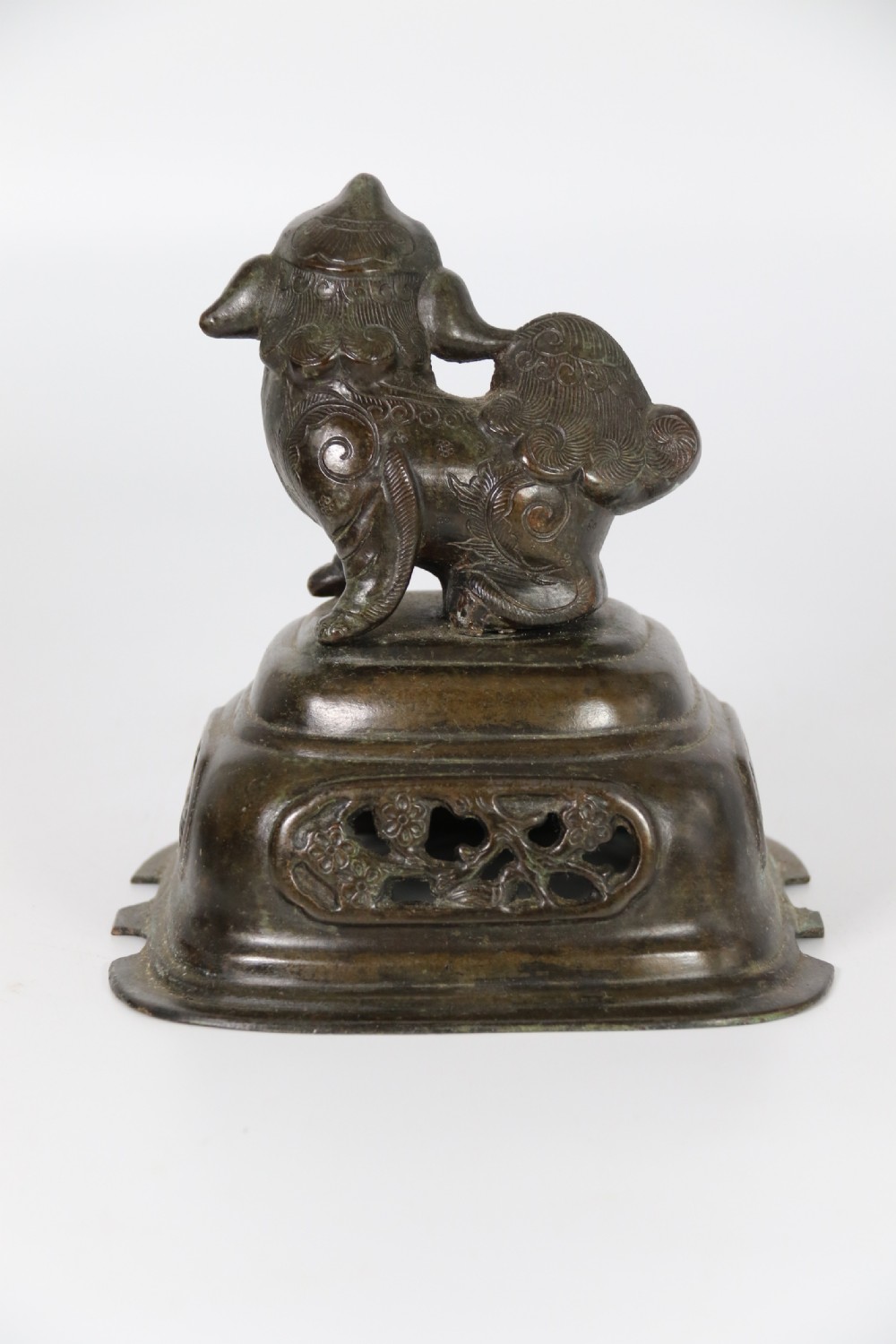 A 19th-century Chinese cast bronze incense censer featuring a lid surmounted by a guardian lion finial, relief panels, and animal-mask handles, set upon a matching bronze base. View XXIII