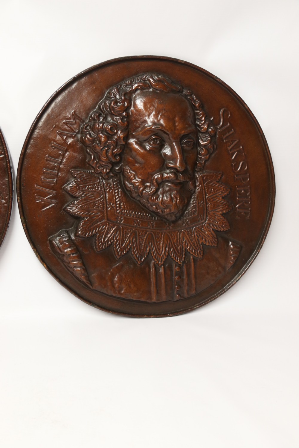 A matched pair of circular dark brown cast iron relief plaques featuring high-relief portrait busts of Peter Paul Rubens and William Shakespeare. View III