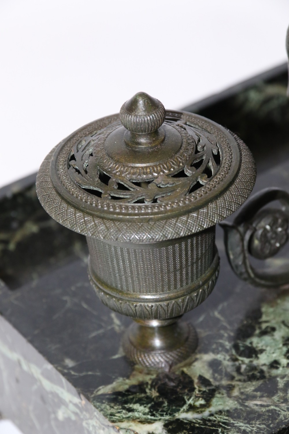 An Empire period dark green marble inkstand featuring dark patinated bronze cherub figures, twin urn inkwells, and carved claw feet. View XXVI