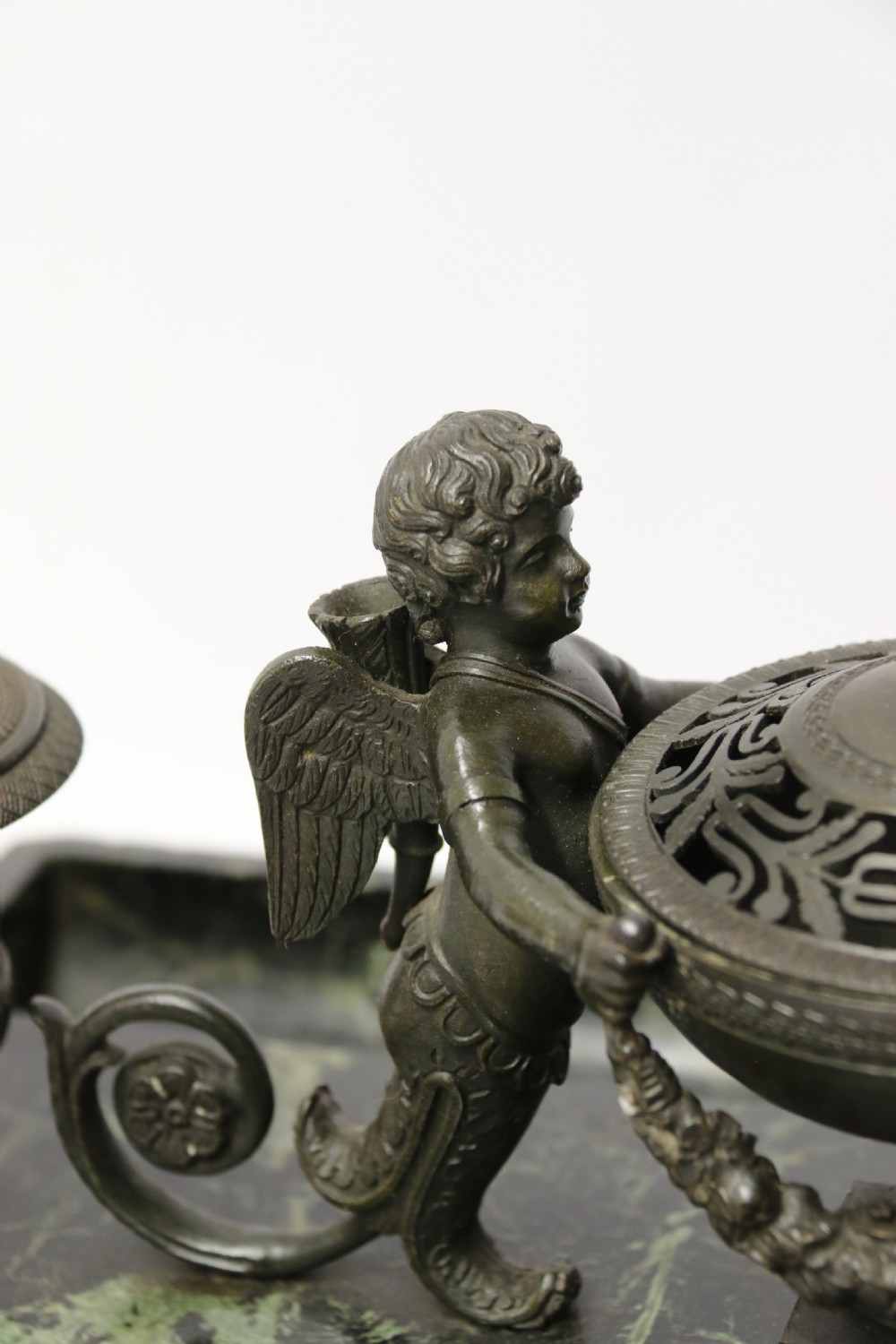 An Empire period dark green marble inkstand featuring dark patinated bronze cherub figures, twin urn inkwells, and carved claw feet. View XXVII