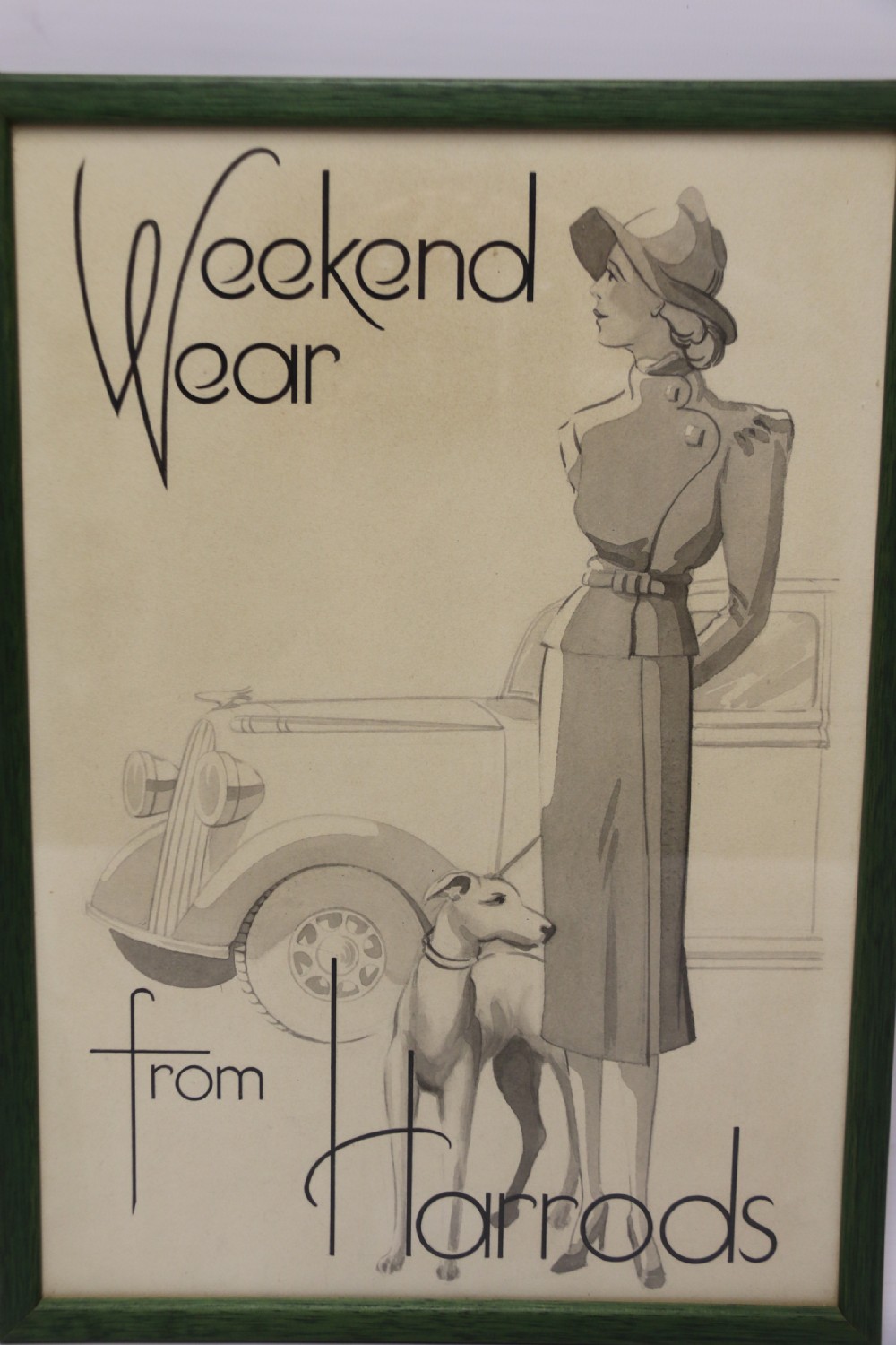 A framed original 1940s sepia monochrome watercolour illustration advertising Harrods weekend wear, featuring a smartly dressed woman, a greyhound dog, and a classic car in a green wooden frame. View IV
