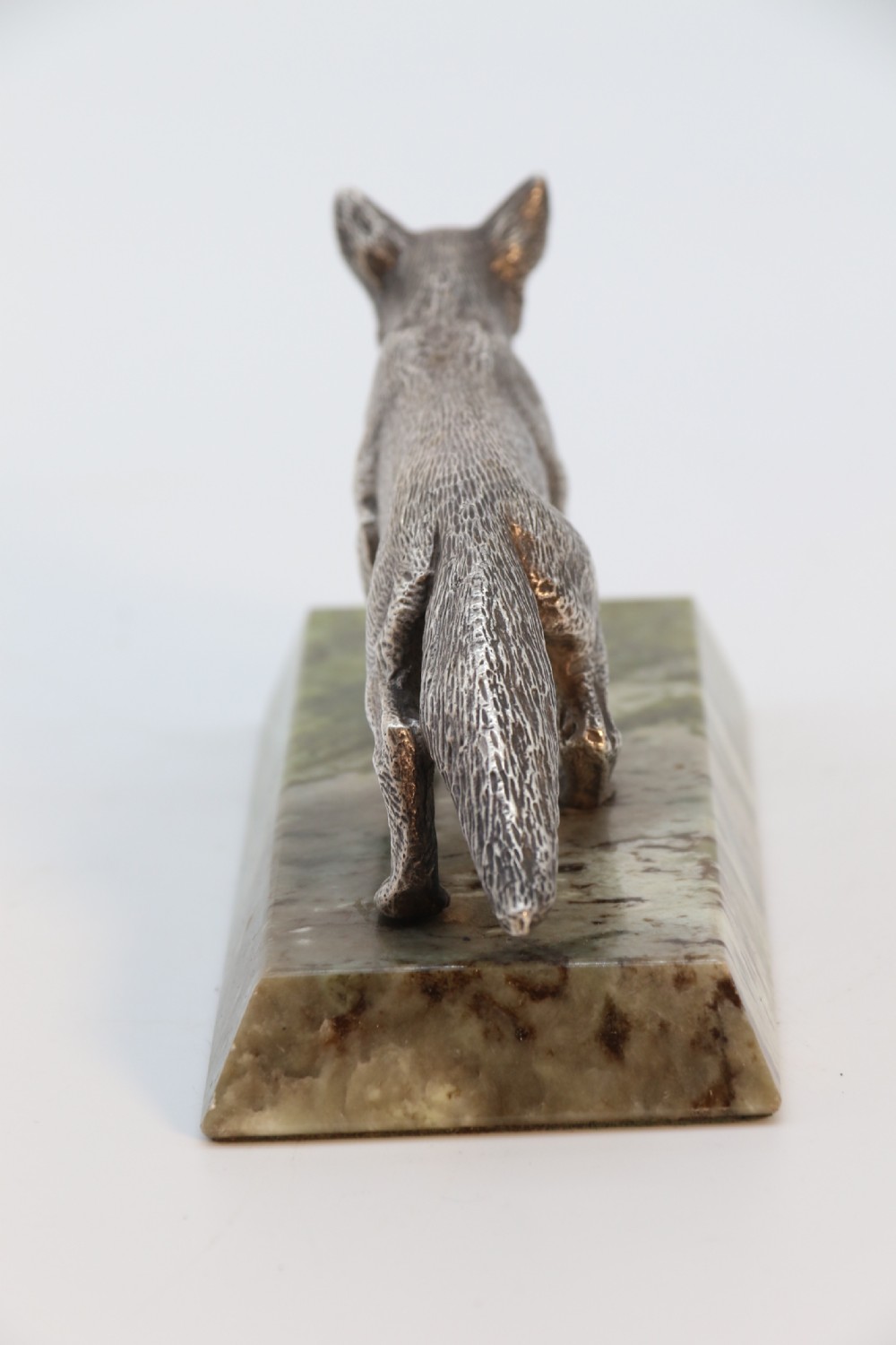 A silvered bronze sculpture depicting a prowling fox mounted on a rectangular green marble plinth. View II