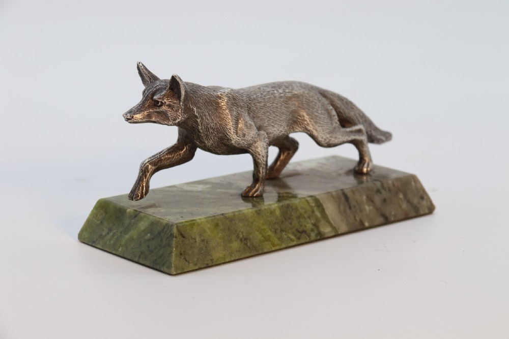 A silvered bronze sculpture depicting a prowling fox mounted on a rectangular green marble plinth. View VII