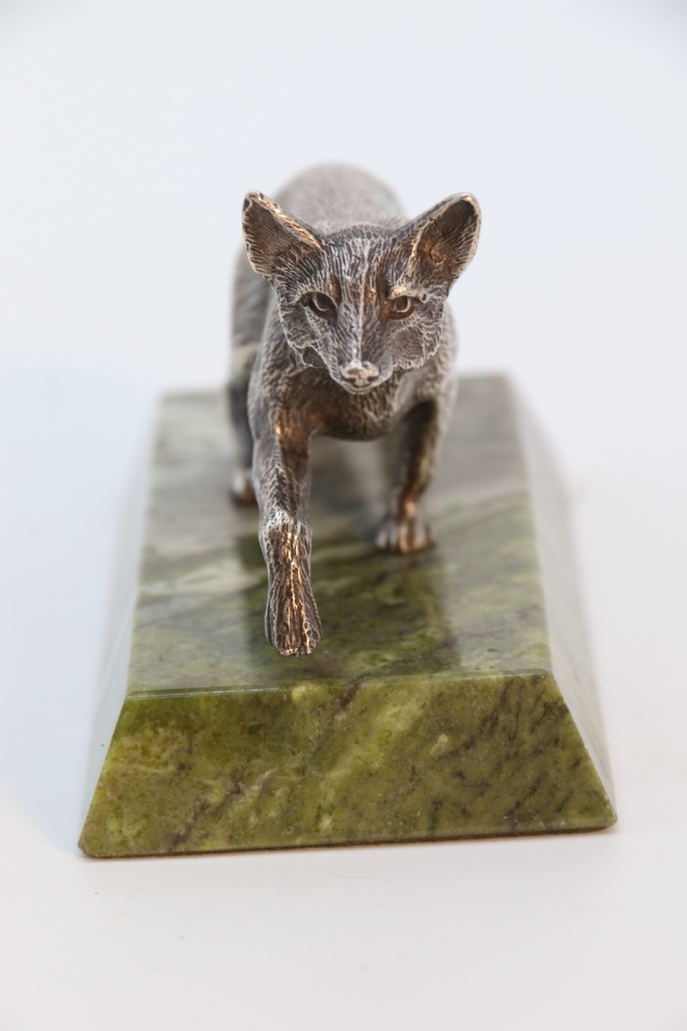 A silvered bronze sculpture depicting a prowling fox mounted on a rectangular green marble plinth. View VIII